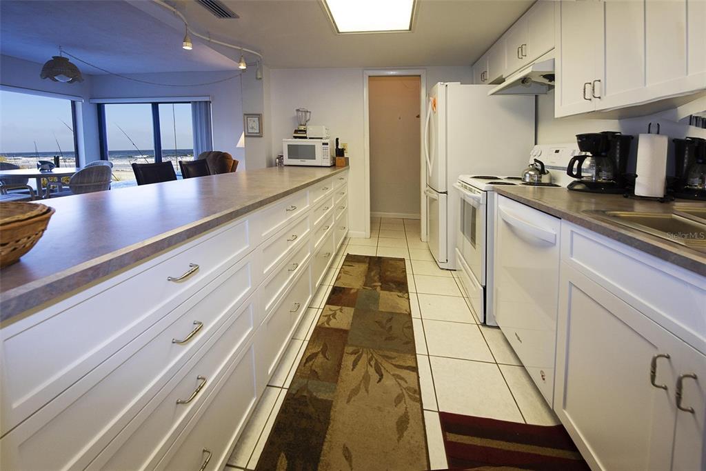 A white kitchen with a long breakfast bar, tile floors, and a view of the ocean — 1571 S ATLANTIC AVENUE UNIT 111, NEW SMYRNA BEACH, FL