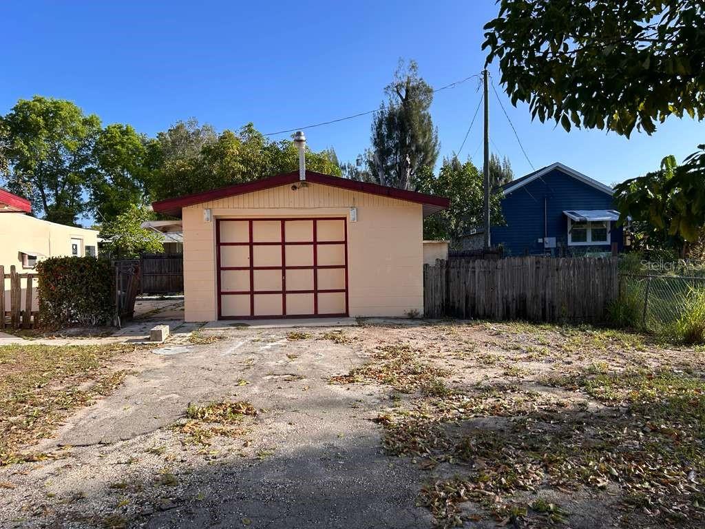 A detached, light-colored garage with a red-trimmed door sits at the end of a driveway — 340 SANTA BARBARA STREET, NORTH FORT MYERS, FL