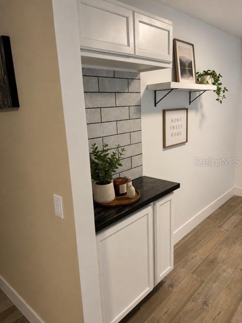 A built-in wet bar features white cabinets, a dark countertop, and gray subway tile backsplash — 905 AVENUE E NE, WINTER HAVEN, FL