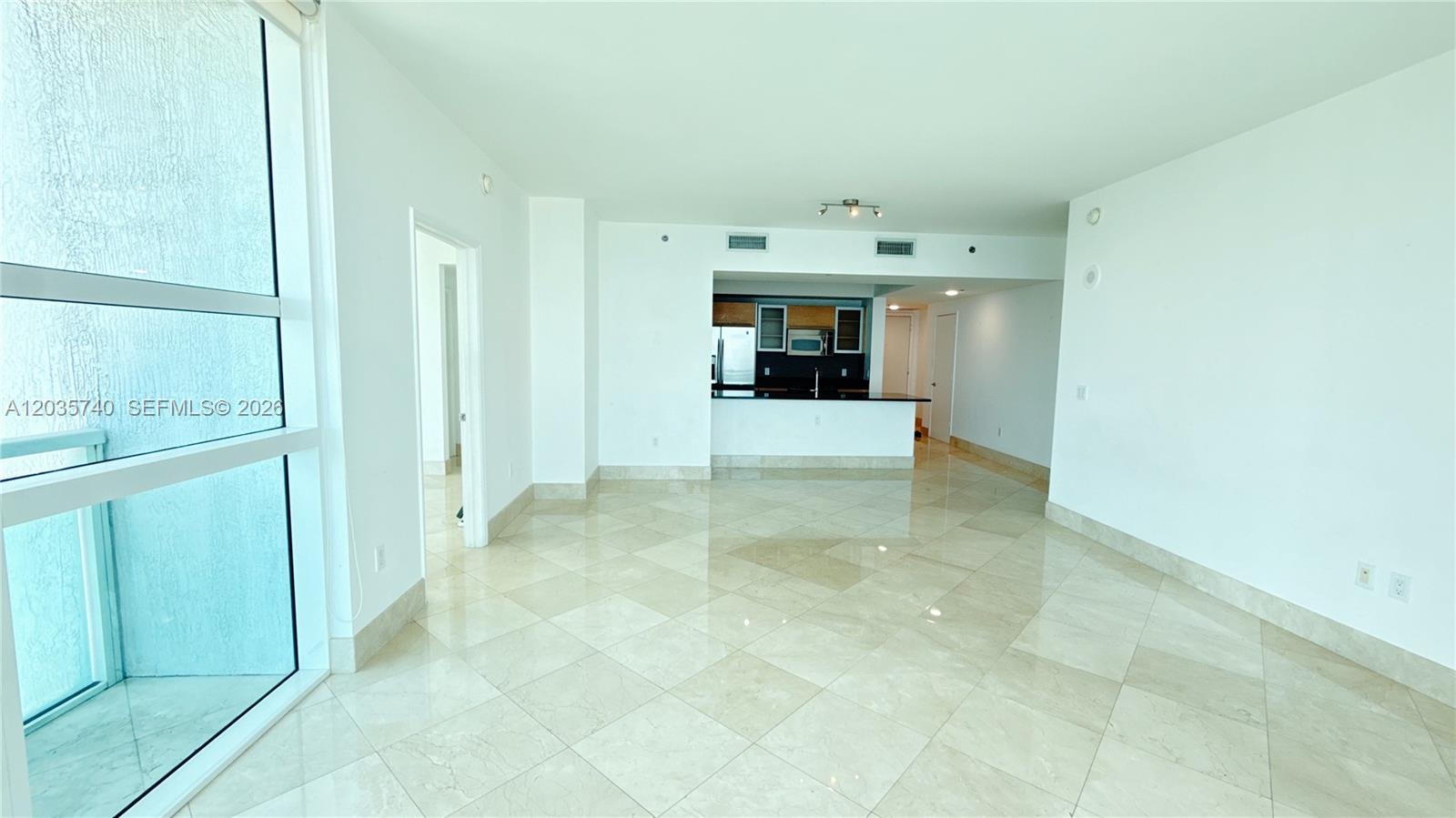An open-concept living area features light-colored tile flooring, white walls, and a kitchen pass-through — 950 Brickell Bay Dr # 3411, Miami FL 33131, MIAMI, FL