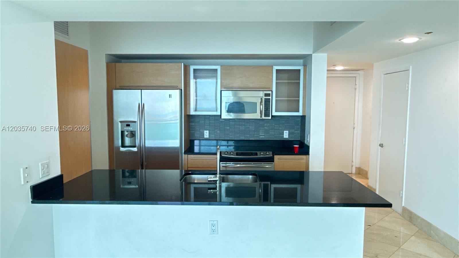 A kitchen features a black granite island, stainless steel appliances, and light wood cabinetry — 950 Brickell Bay Dr # 3411, Miami FL 33131, MIAMI, FL