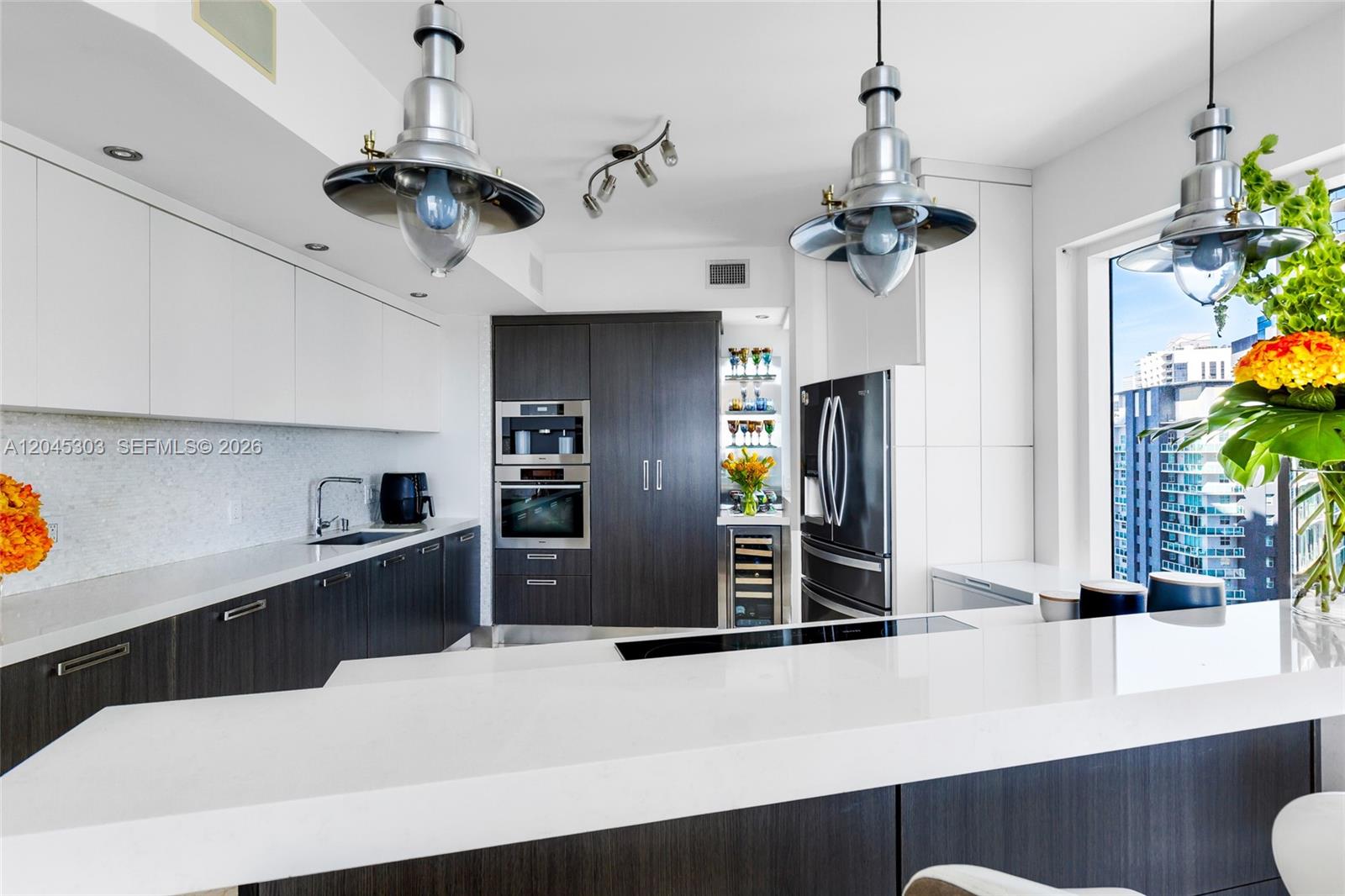 A modern kitchen features dark wood cabinetry, white countertops, stainless steel appliances, and industrial lighting — 60 SW 13th St # 3200, Miami FL 33130, MIAMI, FL