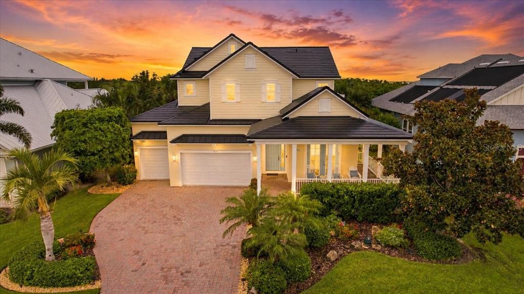 A two-story yellow house with a dark roof and a brick driveway at sunset — 8124 37TH AVENUE CIRCLE W, BRADENTON, FL