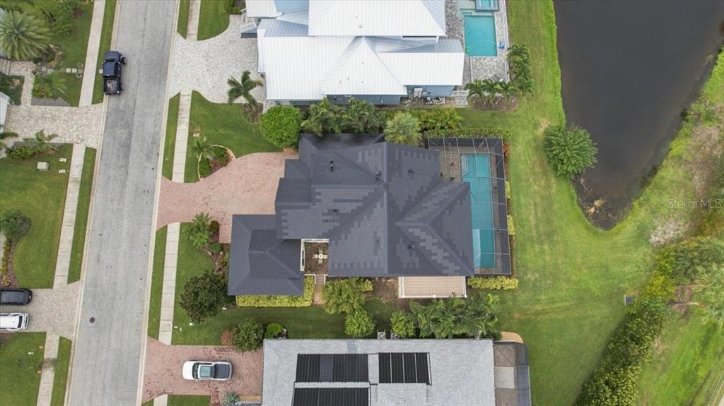 An aerial view shows a house with a dark roof, a screened pool, and landscaping — 8124 37TH AVENUE CIRCLE W, BRADENTON, FL