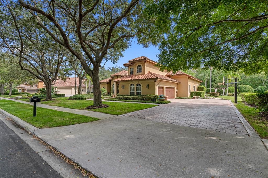 An aerial view of a house with a tiled roof, screened pool, and landscaped backyard — 531 ISLEWORTH CLOSE, TARPON SPRINGS, FL