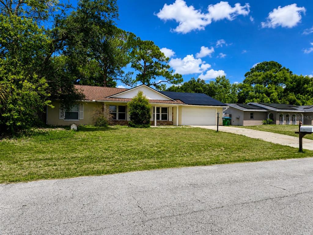 A single-story house with a white garage, solar panels on the roof, and a front lawn — 1432 LANDOVER AVENUE, DELTONA, FL