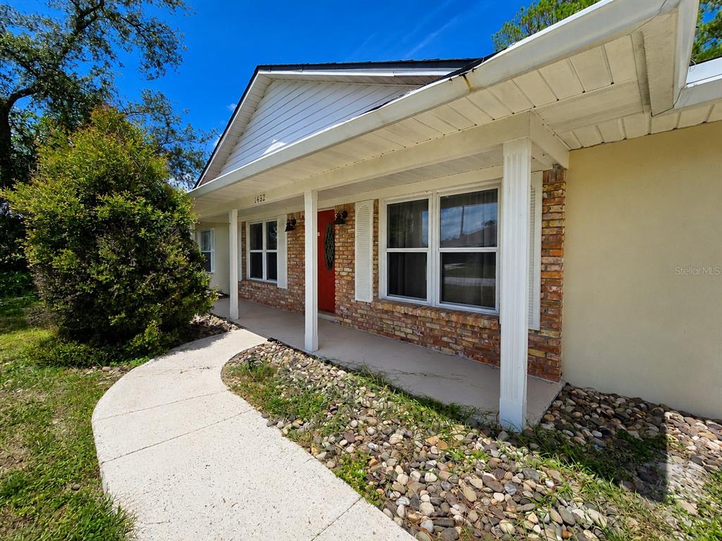 A single-story house exterior features a brick facade, a covered porch, and a concrete walkway — 1432 LANDOVER AVENUE, DELTONA, FL