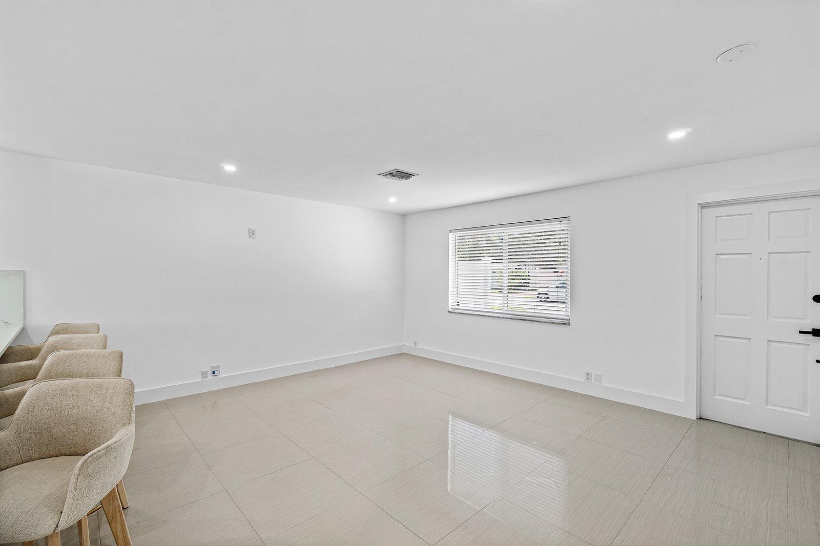 A bright, minimalist room features white walls, large light-colored floor tiles, and a window — 1531 NW 4th Street, Boca Raton FL 33486, BOCA RATON, FL