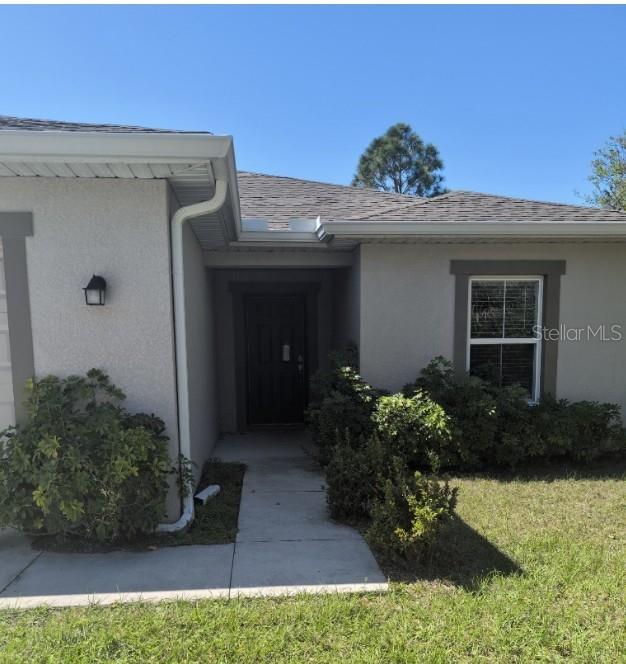 A single-story house with a recessed dark front door, a window, and surrounding landscaping — 26245 NORTHERN CROSS ROAD, PUNTA GORDA, FL