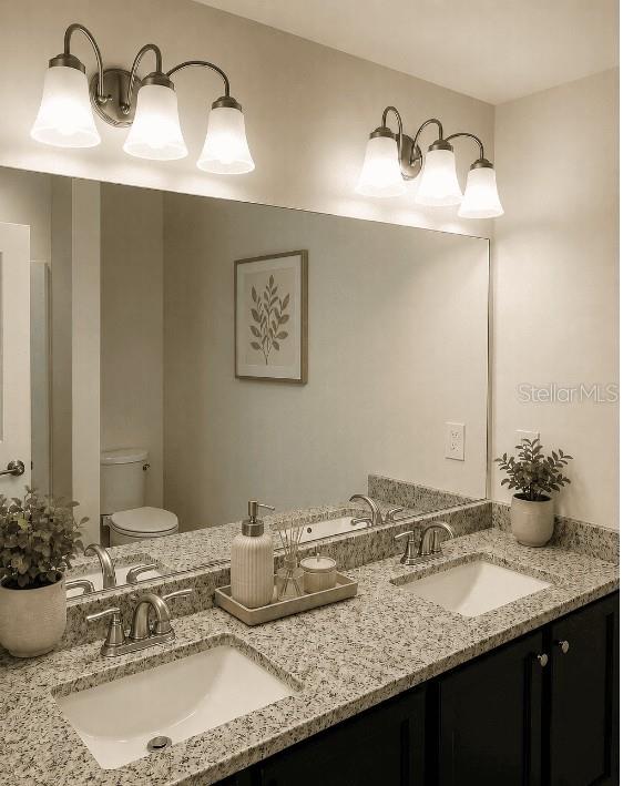 A bathroom features a double vanity with granite countertops, dark cabinets, and two wall-mounted light fixtures — 26245 NORTHERN CROSS ROAD, PUNTA GORDA, FL