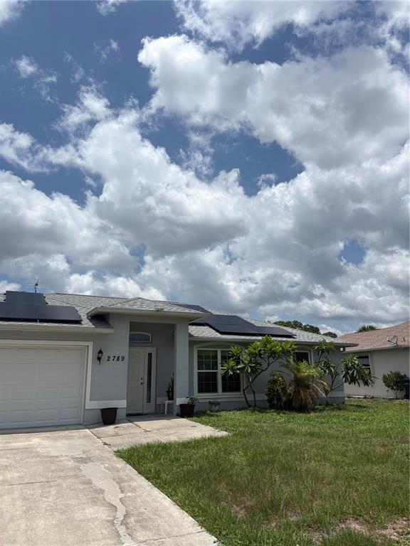 A single-story house with a white garage, solar panels on the roof, and a front yard — 2789 RHUMBA TERRACE, NORTH PORT, FL