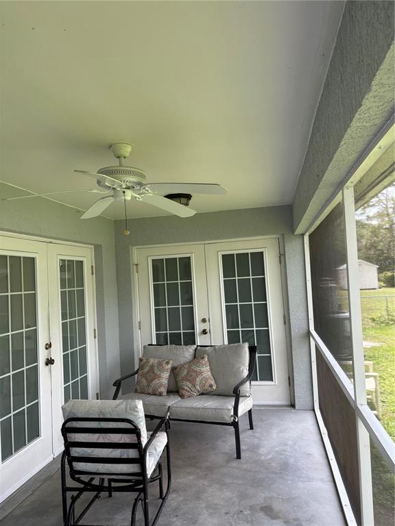 A screened-in patio features a ceiling fan, two sets of French doors, and outdoor furniture — 2789 RHUMBA TERRACE, NORTH PORT, FL
