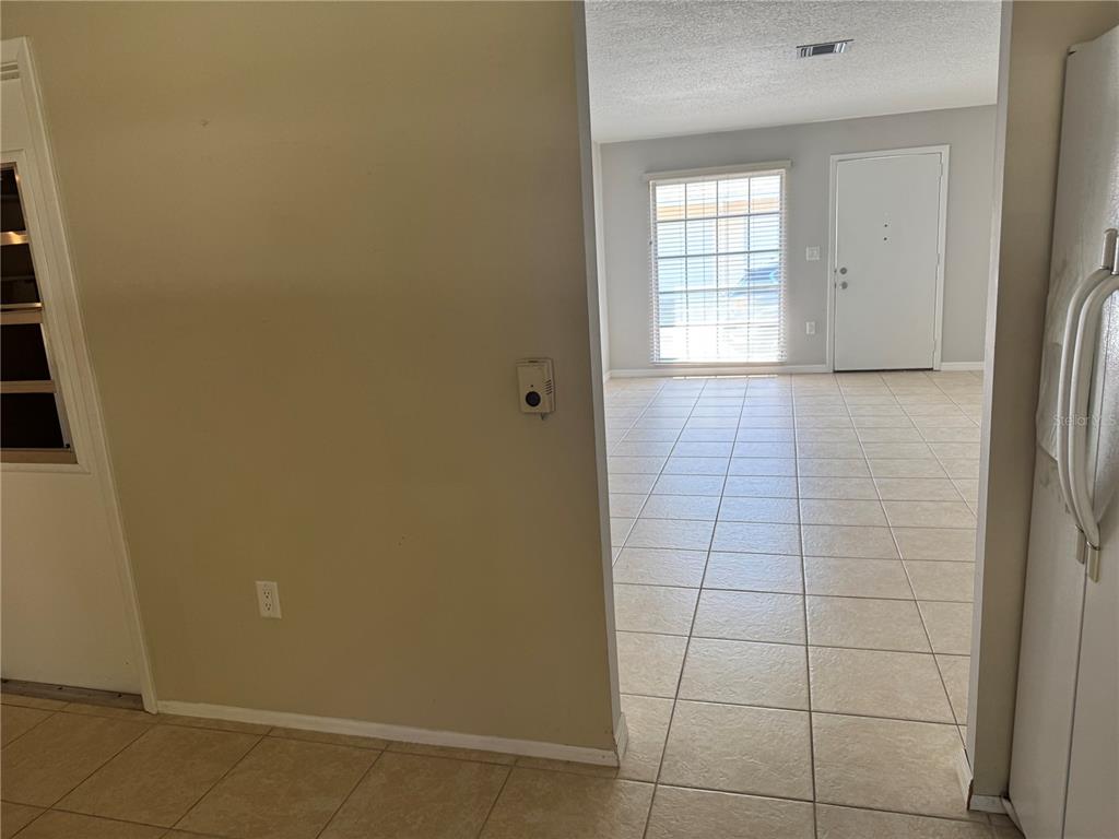 A view from a tiled kitchen into a living area with a front door — 852 OXFORD COURT, DUNEDIN, FL