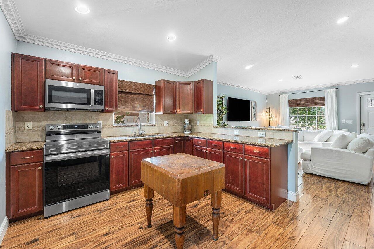 A kitchen with cherry wood cabinets, granite countertops, and a butcher block island — 5418 Club Circle, Haverhill FL 33415, HAVERHILL, FL