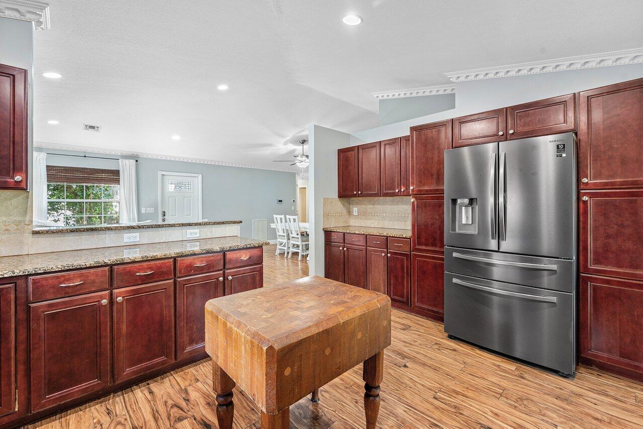 A kitchen features dark wood cabinets, granite countertops, a butcher block island, and stainless appliances — 5418 Club Circle, Haverhill FL 33415, HAVERHILL, FL
