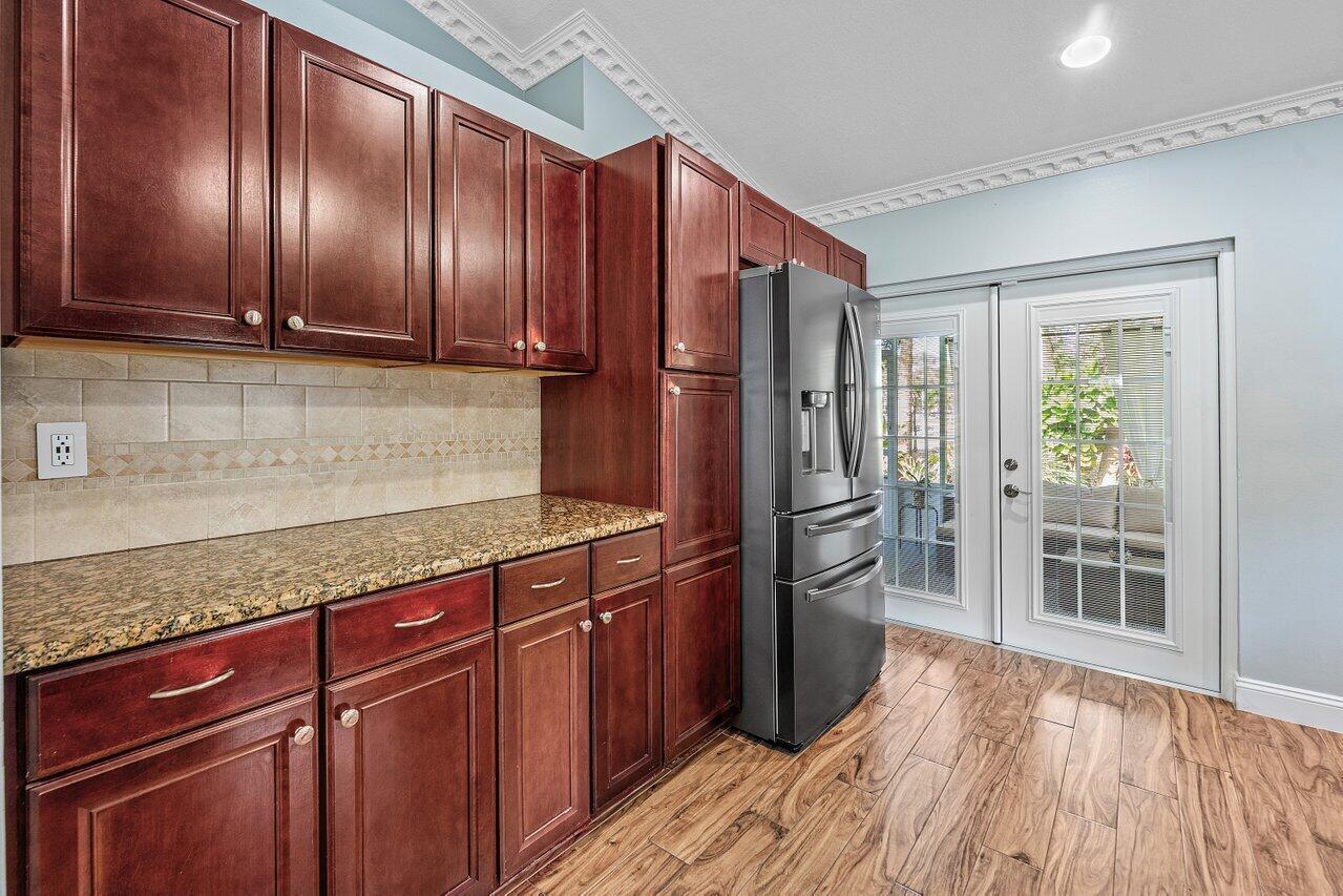 A kitchen features dark wood cabinets, granite countertops, stainless steel appliances, and glass patio doors — 5418 Club Circle, Haverhill FL 33415, HAVERHILL, FL