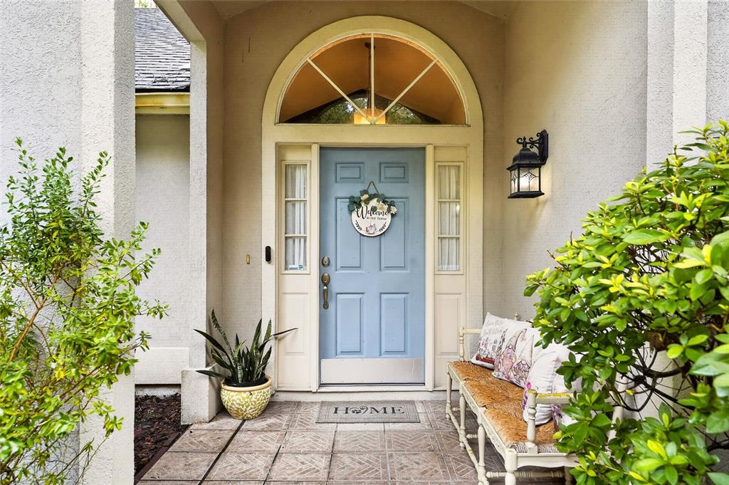 A light blue front door with a transom window and a bench on the porch — 10427 SW 55TH PLACE, GAINESVILLE, FL