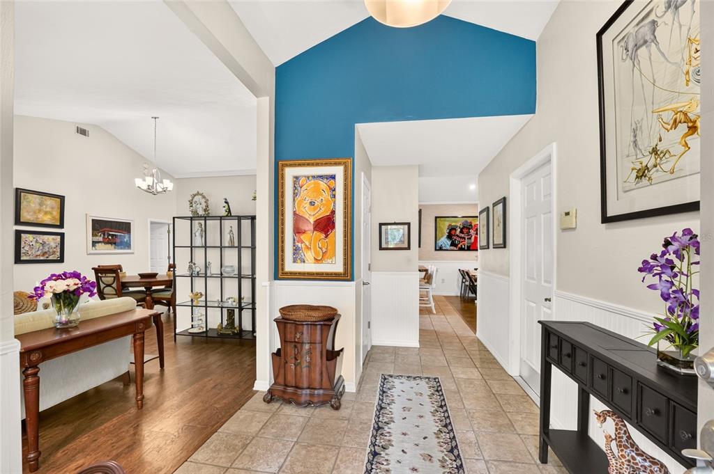 A living room with hardwood floors, a beige sofa, a console table, and a bookshelf — 10427 SW 55TH PLACE, GAINESVILLE, FL