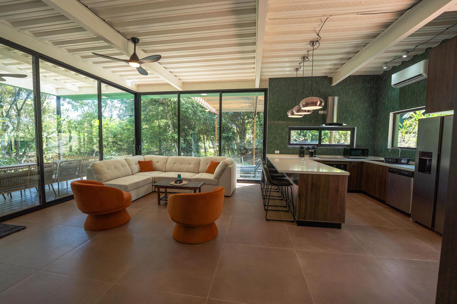 An open-concept living room and kitchen with floor-to-ceiling windows, green tile, and orange chairs — 200 Burn Brae Way, Bocas Del Toro,, FL