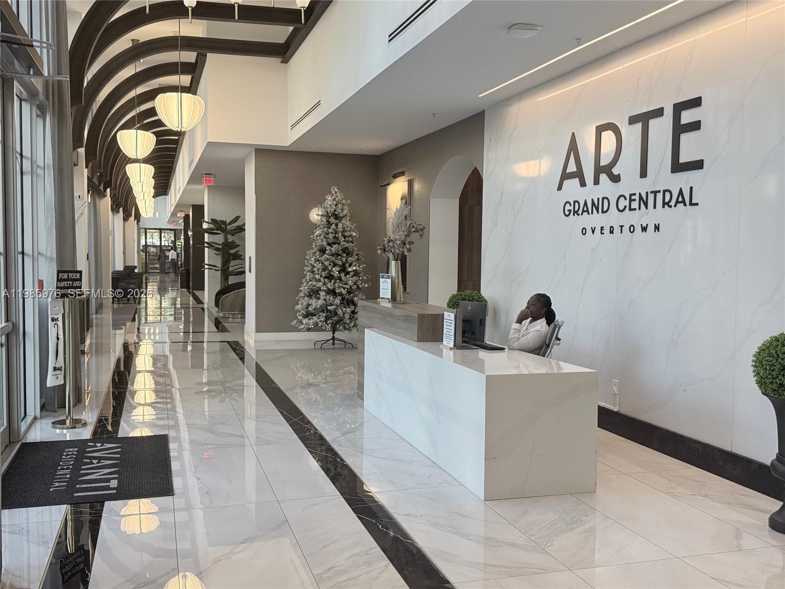 A modern lobby features a marble reception desk, tiled floors, and a decorative Christmas tree — 218 NW 8th St, Miami FL 33136, MIAMI, FL