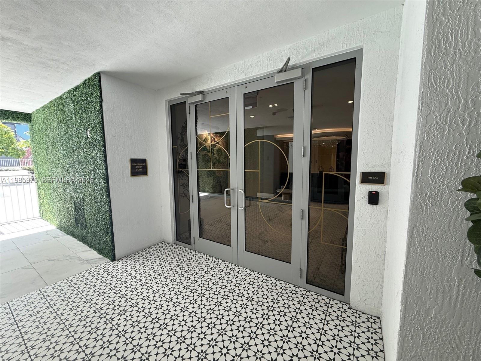 A double glass door entrance to a spa features patterned tile flooring and green walls — 218 NW 8th St, Miami FL 33136, MIAMI, FL