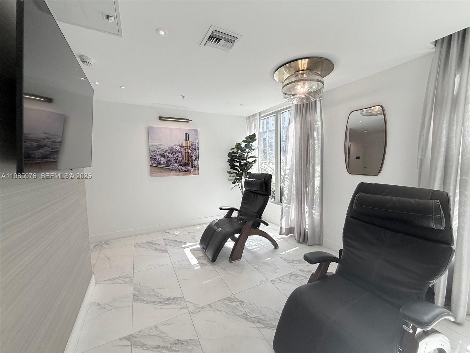 A room features two black reclining chairs, marble-patterned tile floors, and a large wall-mounted television — 218 NW 8th St, Miami FL 33136, MIAMI, FL