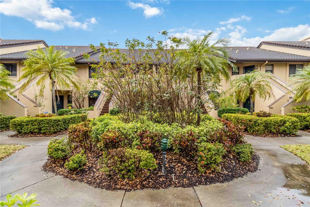 A landscaped courtyard sits in front of a two-story residential building with palm trees — 5734 ASHTON LAKE DRIVE UNIT 7, SARASOTA, FL