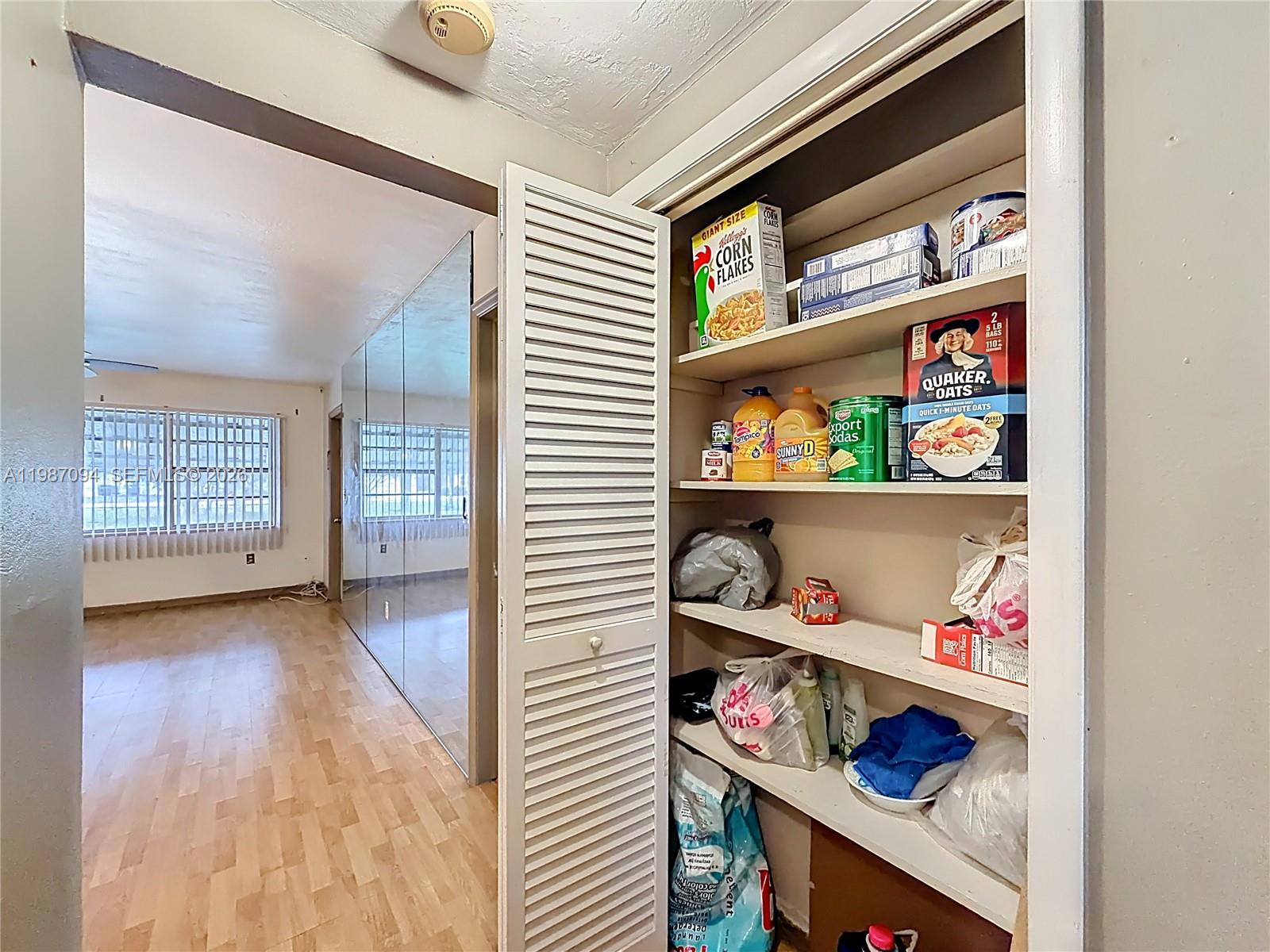 A pantry with louvered doors opens into a room with light wood flooring and mirrored walls — 6730 Arbor Dr # 110, Miramar FL 33023, MIRAMAR, FL