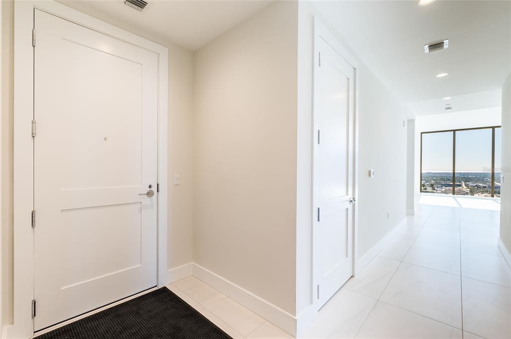 A modern lobby features a marble reception desk, curved seating, and a large light installation — 275 1ST AVE SOUTH UNIT 2606, ST PETERSBURG, FL