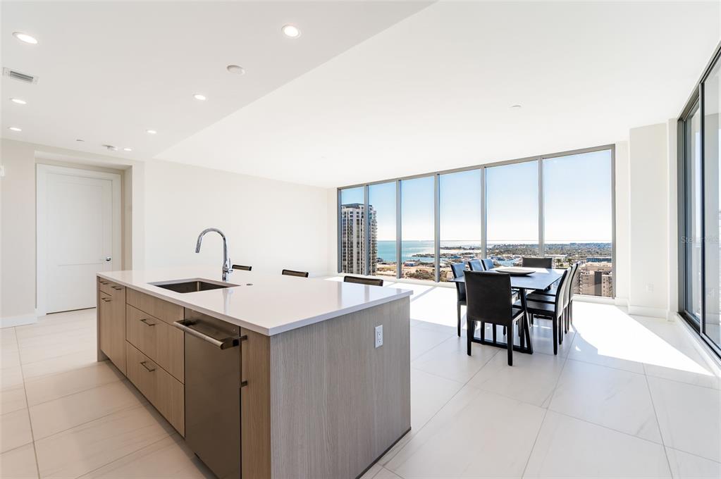 A modern kitchen features light wood cabinetry, white upper cabinets, a large island, and appliances — 275 1ST AVE SOUTH UNIT 2606, ST PETERSBURG, FL