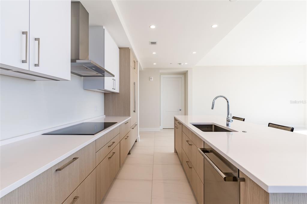 A modern kitchen features light wood cabinetry, white countertops, a large island, and stainless appliances — 275 1ST AVE SOUTH UNIT 2606, ST PETERSBURG, FL