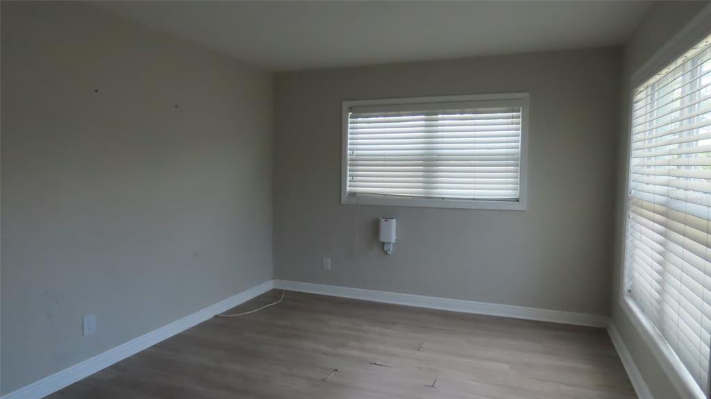 An empty room with light gray walls, wood-look flooring, and two windows with white blinds — 6543 34TH TERRACE N, ST PETERSBURG, FL