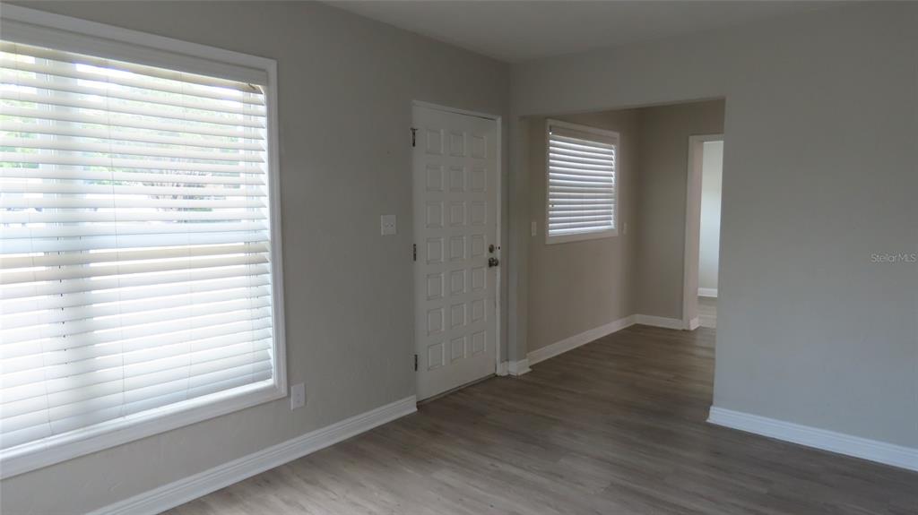 A room with light gray walls, wood-look flooring, a white front door, and window blinds — 6543 34TH TERRACE N, ST PETERSBURG, FL