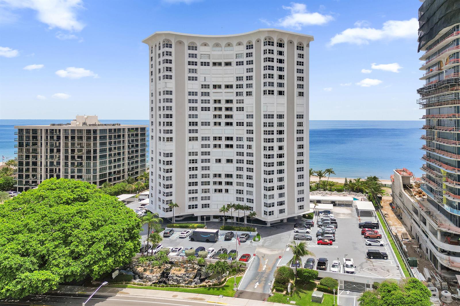 An aerial view shows a tall residential building surrounded by a parking lot and oceanfront — 1340 S Ocean Boulevard # 303, Pompano Beach FL 33062, POMPANO BEACH, FL