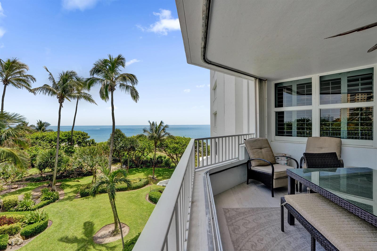 A balcony with outdoor furniture overlooks a lush green lawn and the ocean — 1340 S Ocean Boulevard # 303, Pompano Beach FL 33062, POMPANO BEACH, FL