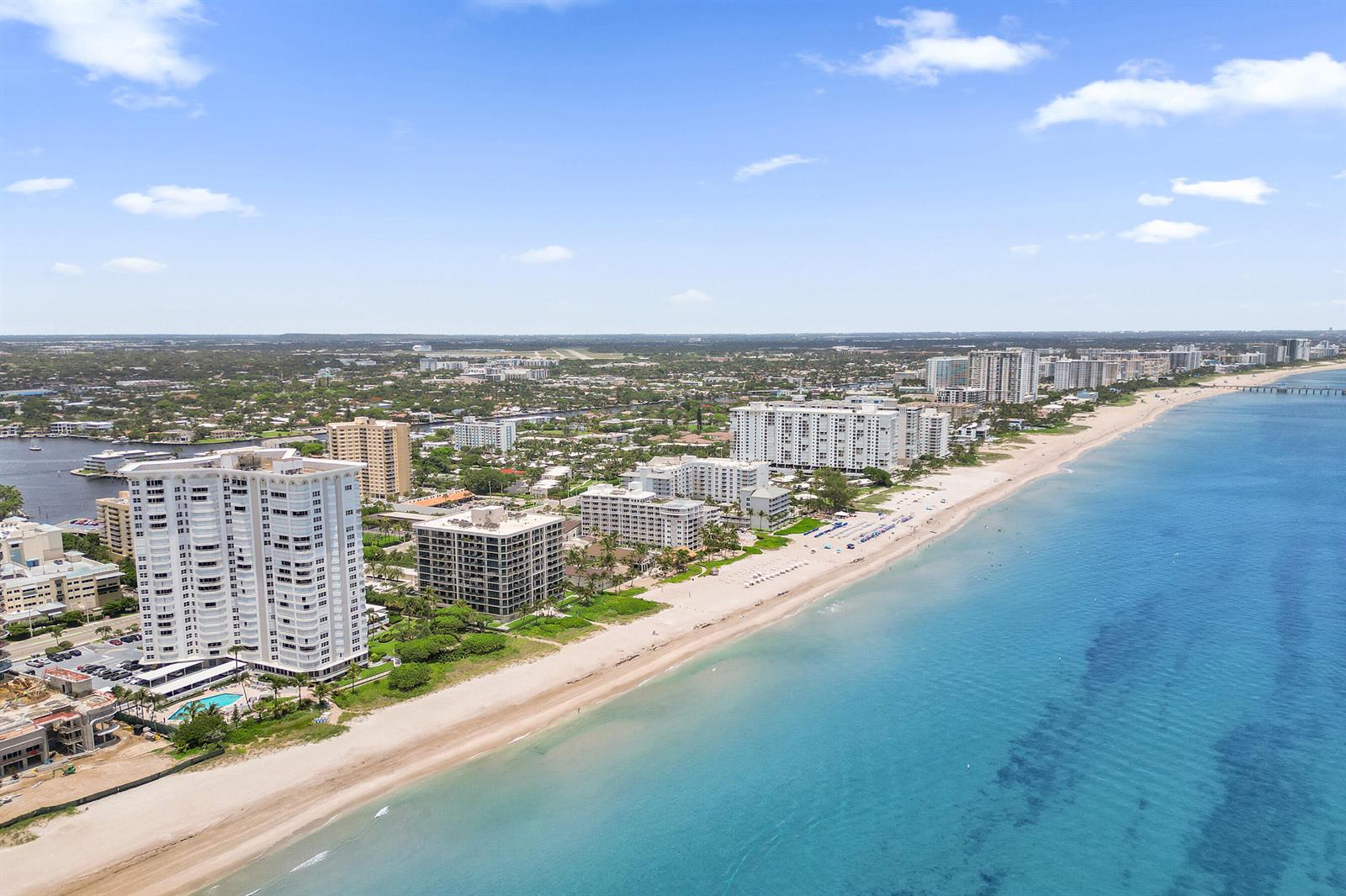 An aerial view shows high-rise apartment buildings along a sandy beach and the ocean — 1340 S Ocean Boulevard # 303, Pompano Beach FL 33062, POMPANO BEACH, FL