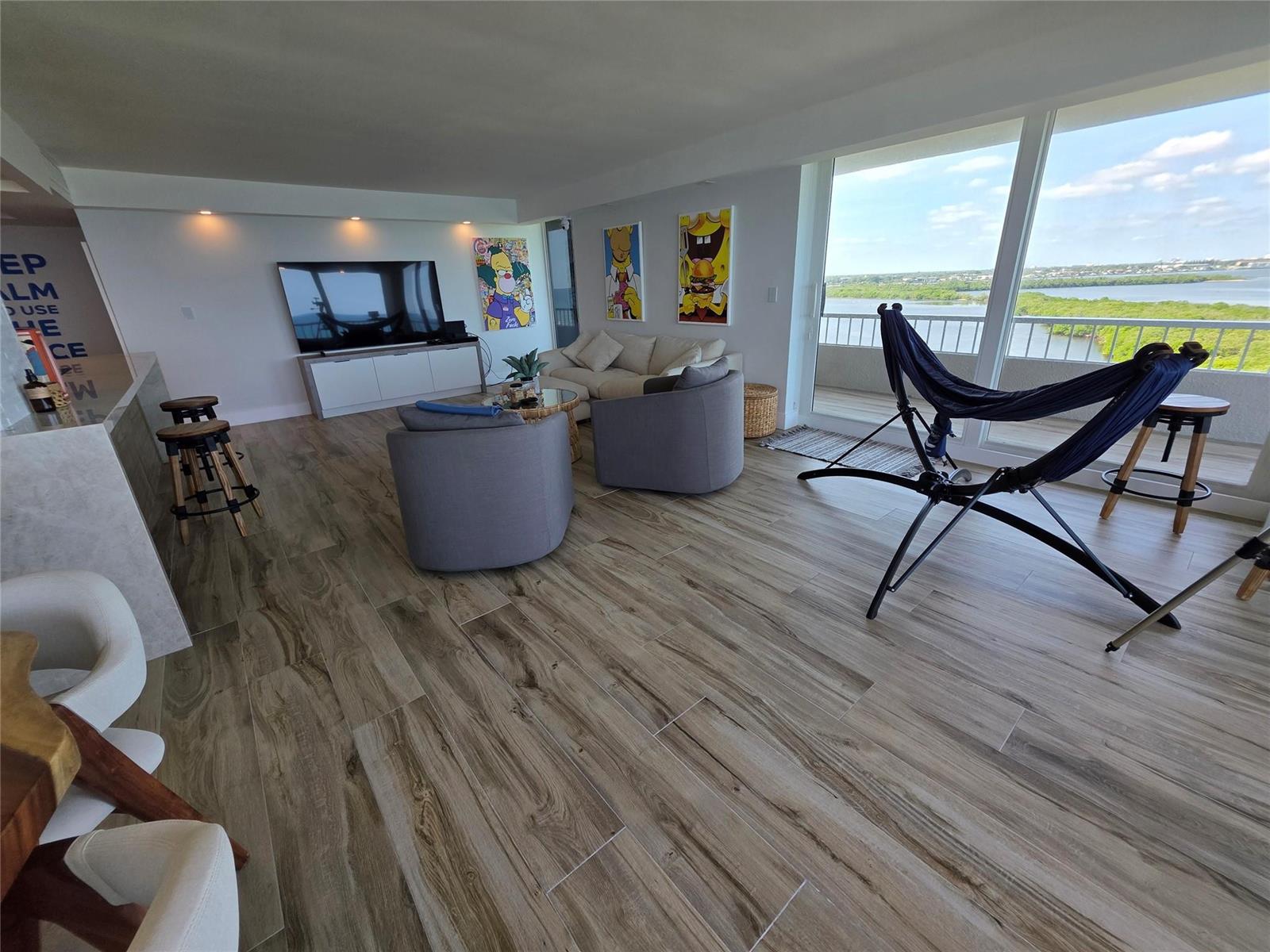 A living room features wood-look tile floors, a hammock, and floor-to-ceiling windows overlooking water — 5550 N Ocean Drive, Riviera Beach FL 33404, RIVIERA BEACH, FL