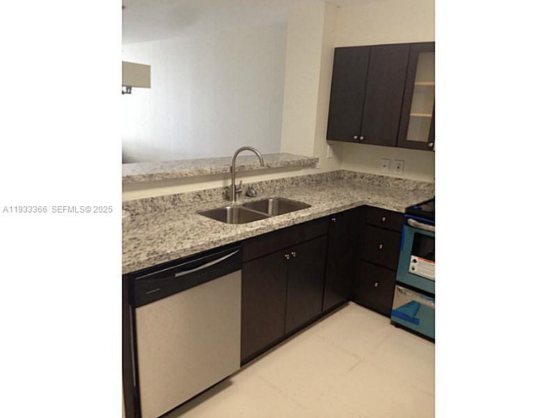 A kitchen features dark wood cabinets, granite countertops, a stainless steel dishwasher, and a sink — 4350 NW 107th Ave # 102, Doral FL 33178, DORAL, FL