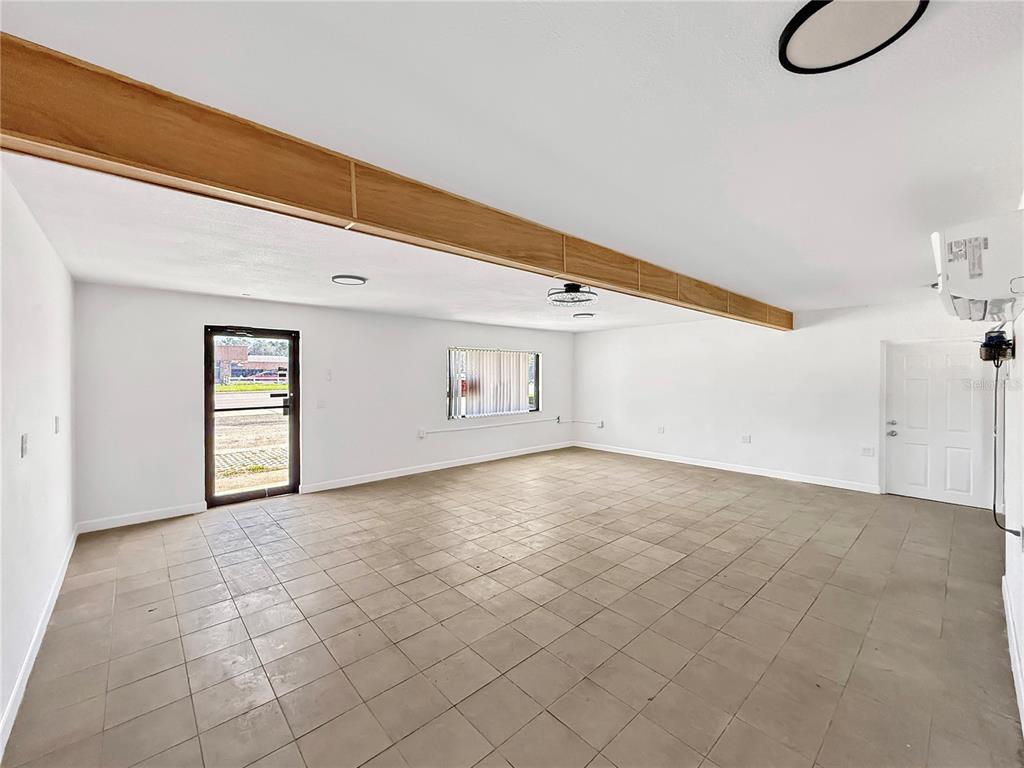 An empty room with white walls, a tiled floor, and a prominent wooden ceiling beam — 1130 N RONALD REAGAN BOULEVARD, LONGWOOD, FL