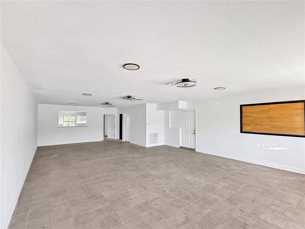 A large, empty room with white walls, tile flooring, recessed lighting, and a wood-framed mirror — 1130 N RONALD REAGAN BOULEVARD, LONGWOOD, FL