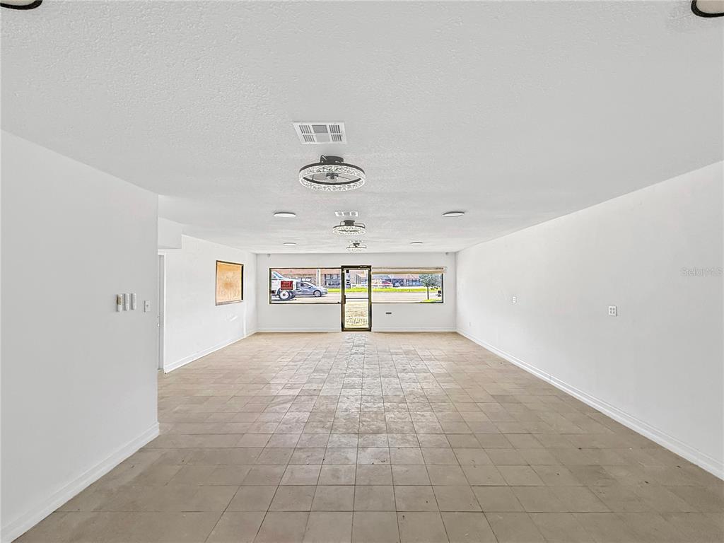 An empty commercial space features white walls, tiled flooring, and two ceiling fans — 1130 N RONALD REAGAN BOULEVARD, LONGWOOD, FL