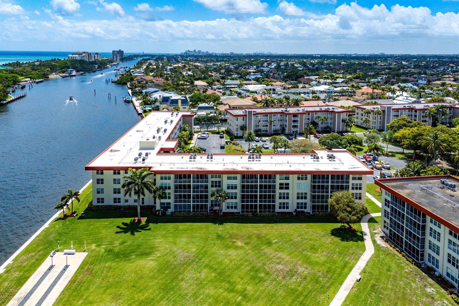 An aerial view shows a multi-story apartment complex situated along a canal with green lawns — 3100 NE 48th Court # 415, Lighthouse Point FL 33064, LIGHTHOUSE POINT, FL