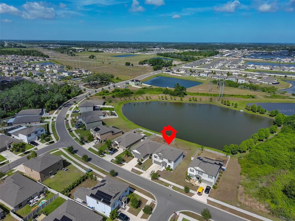 An aerial view shows a suburban neighborhood with houses, a pond, and surrounding green space — 1507 GOLDEN GLOW DRIVE, RUSKIN, FL
