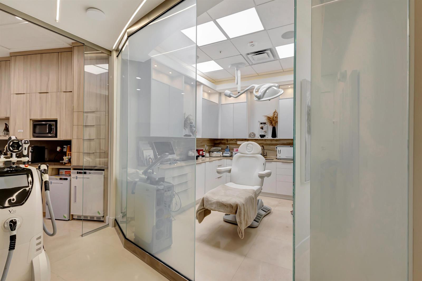A modern medical spa treatment room features a white procedure chair behind a glass partition — 2151 Fl A1aalt, Jupiter FL 33477, JUPITER, FL