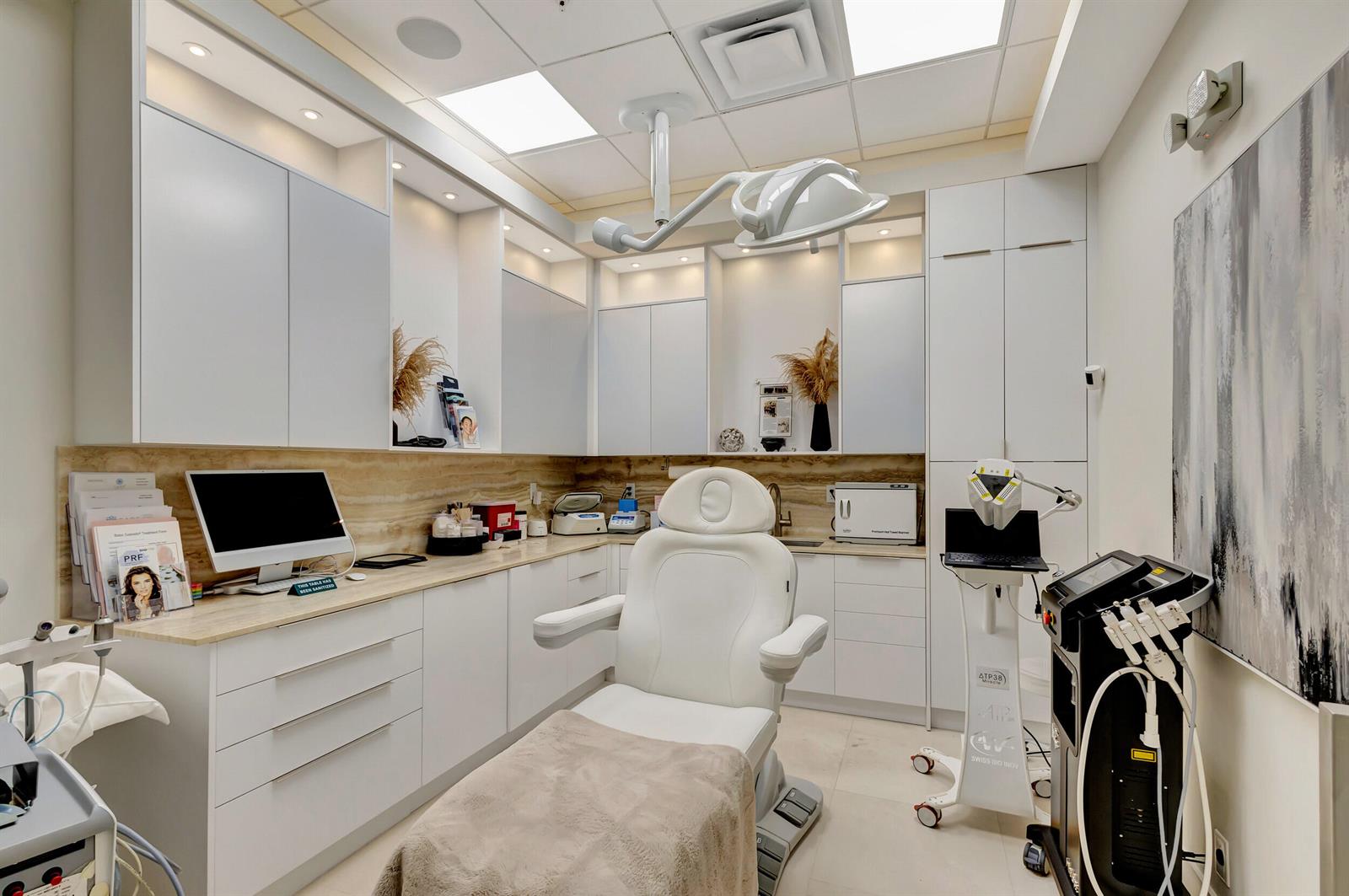 A modern medical aesthetic treatment room features a white procedure chair, cabinetry, and specialized equipment — 2151 Fl A1aalt, Jupiter FL 33477, JUPITER, FL