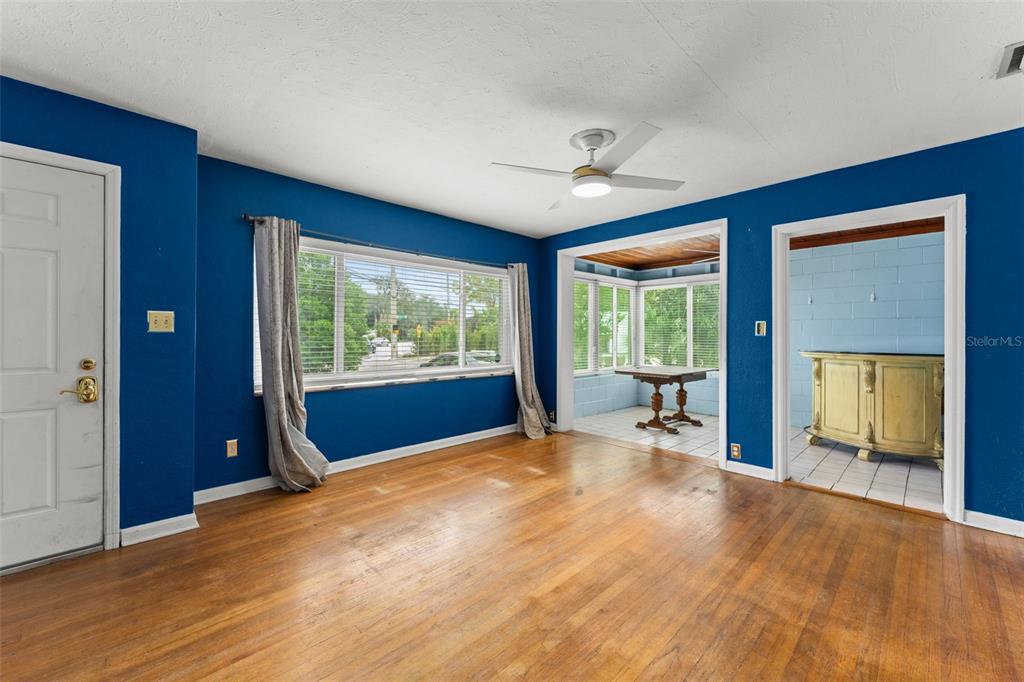A living room with blue walls, hardwood floors, and an adjacent sunroom — 1714 N BUMBY AVENUE, ORLANDO, FL