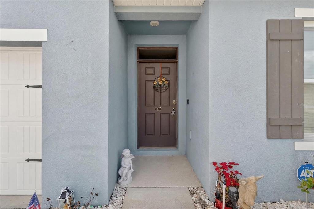 A brown front door with a wreath is set within a light blue stucco entryway — 2658 GRANDBURY GROVE ROAD, LAKELAND, FL
