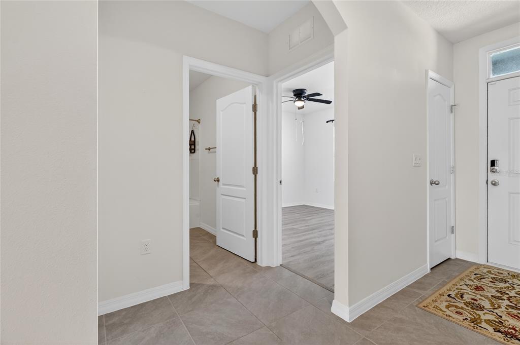 An interior hallway features tile flooring, white doors, and an entrance to a bedroom — 2658 GRANDBURY GROVE ROAD, LAKELAND, FL