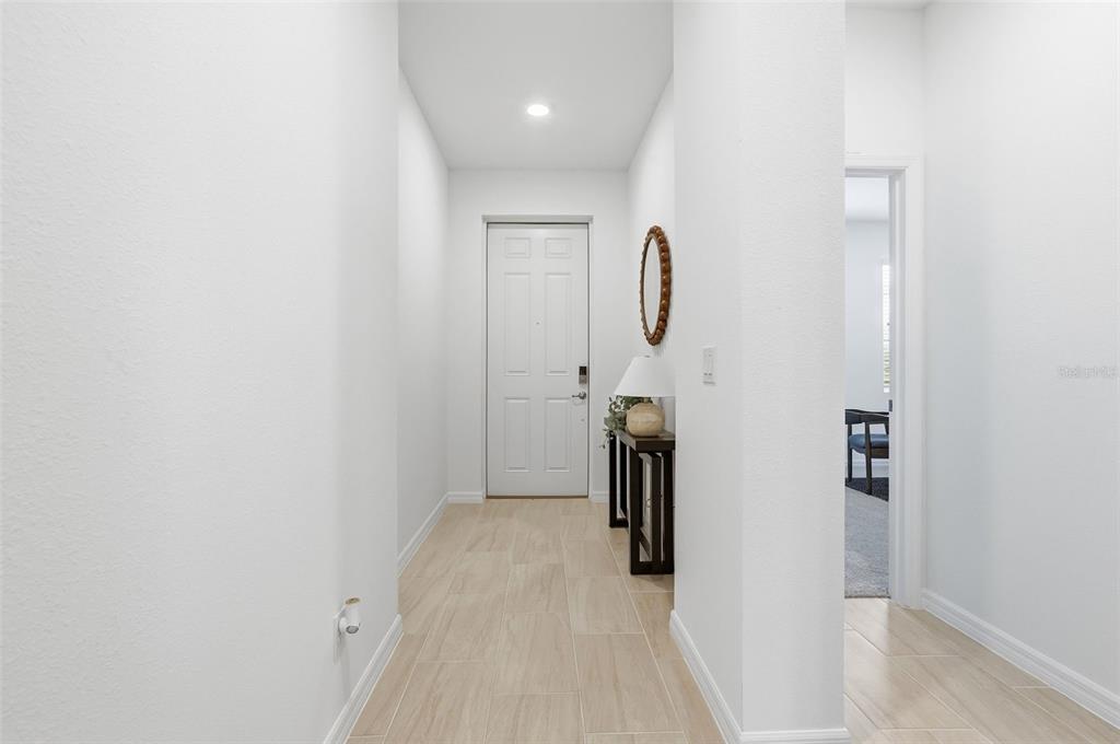 A bright entryway features white walls, light tile flooring, a front door, and a console table — 725 FARFIELDS STREET, DELAND, FL