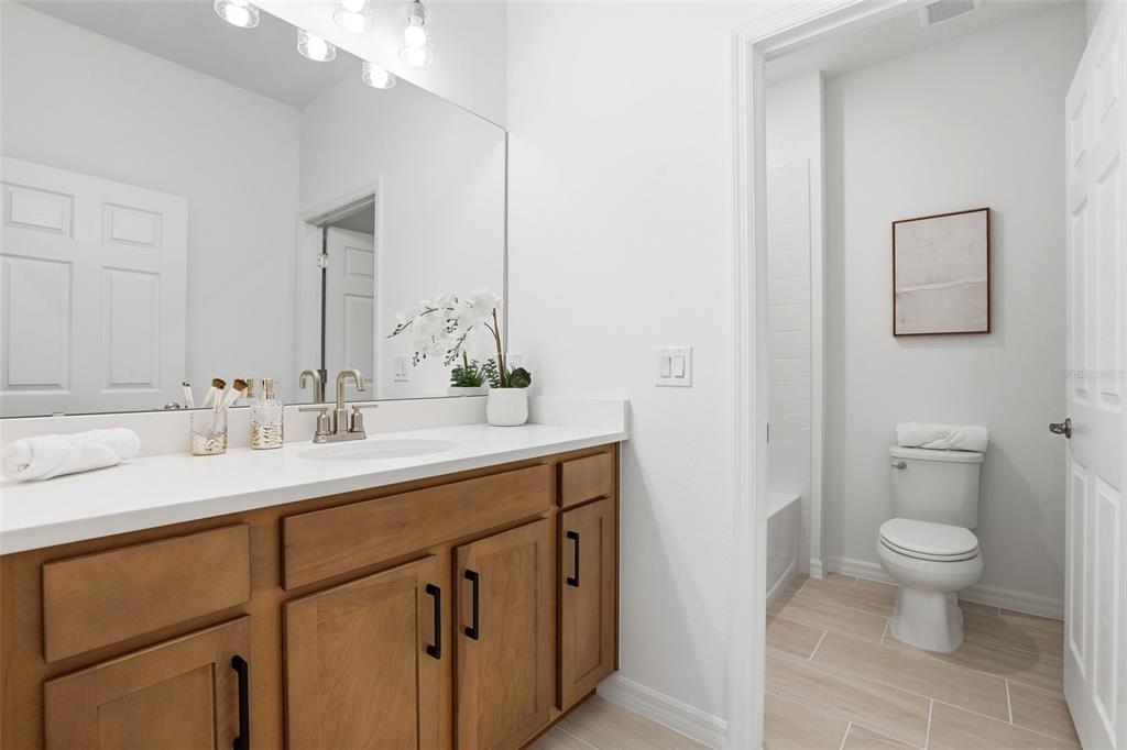 A bathroom features a wooden vanity with a white countertop and an adjacent toilet area — 725 FARFIELDS STREET, DELAND, FL